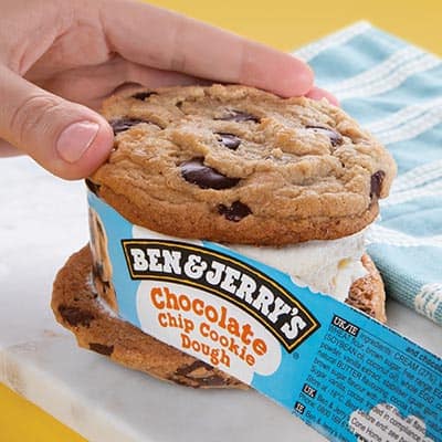 Hand peels the ice cream pint packaging away from the ice cream.