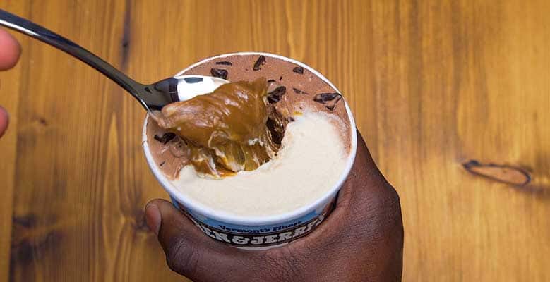 Pint of Ben & Jerry's, hand digs into center of ice cream