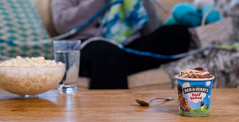 Person on couch with pint of Half Baked ice cream