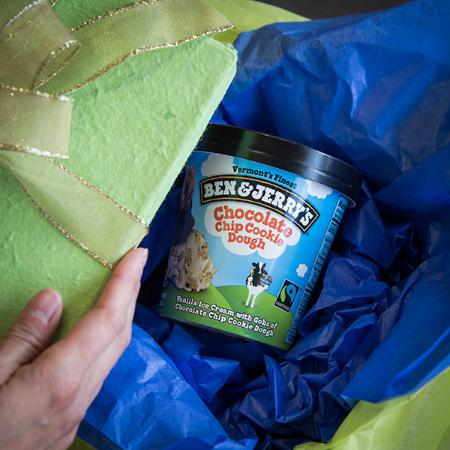 A pint of Ben & Jerry's Chocolate Chip Cookie Doughin a box being unwrapped